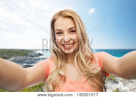 travel, tourism, emotions, expressions and people concept - happy smiling young woman taking selfie over exotic tropical beach background