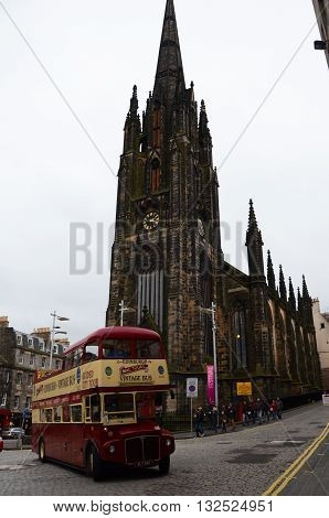 Vintage tour bus passes in front of Edinburgh Cathedral in a cloudy day, October 20, 2015
