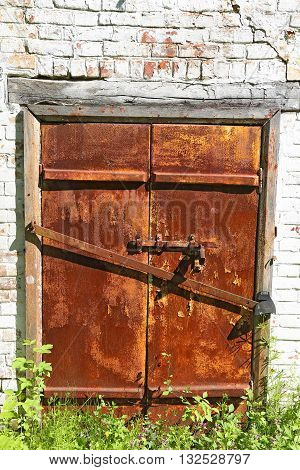 Old iron rusty door with bolt on an ancient brick wall - gated entrance to the basement