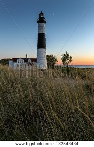 Moon over Big Sable Lighthouse along the shores of Lake Michigan at sunset.