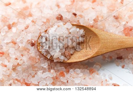Pink Himalayan salt. Himalayan salt pile. Pink crystal salt  in wooden spoon. Close up Himalayan salt - pink and orange coarse crystals.