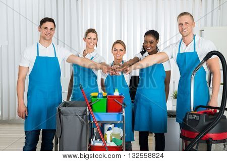 Group Of Happy Cleaners In Uniform Stacking Hands At Workplace