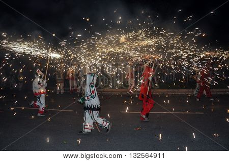 Traditional correfocs (fire runs) or Ball de Diables spectacle. Group of people dressed as devils and dancing with lighting fireworks fixed on devil's pitchforks. Reus Spain.