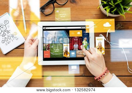 business, education, technology, people and mass media concept - close up of woman with internet news application on tablet pc computer screen on wooden table