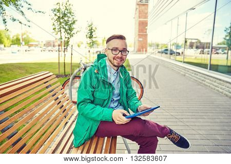 people, style, technology and lifestyle - happy young hipster man with tablet pc computer and fixie bike sitting on bench in city