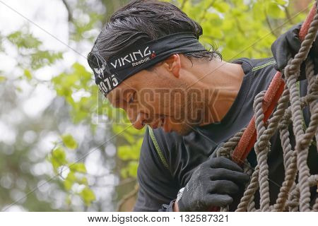 STOCKHOLM SWEDEN - MAY 14 2016: Closeup of a man climbing up a net in the obstacle race Tough Viking Event in Sweden May 14 2016