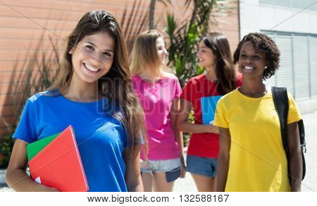 Caucasian female student in red shirt with other international students outdoor in the city