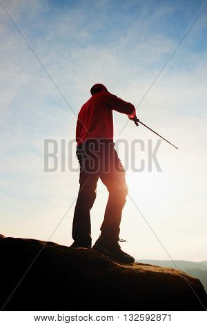 Tourist In Windcheater With Sporty Trecking  Poles In Hands Stand On Rocky View Point. Spring Commin