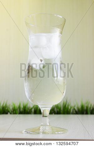 misted Glass of water with ice on blur green background.