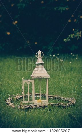 Lantern on the grass in the style of vintage mid woven wooden wreath