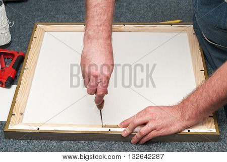 Craftsman working on frame in frame shop. Professional framer hand holding frame angle. Copy space. Top view.
