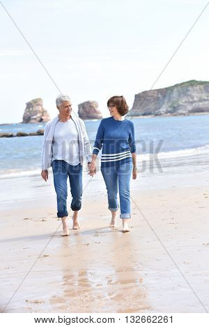 Senior people walking on sandy beach