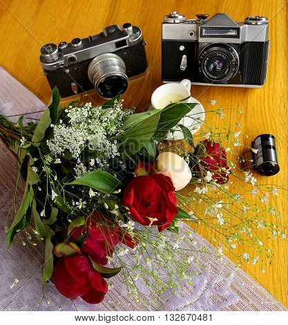 Beautiful Vintage Cameras with a colorful bouquet of flowers and decorative candles on the wooden table