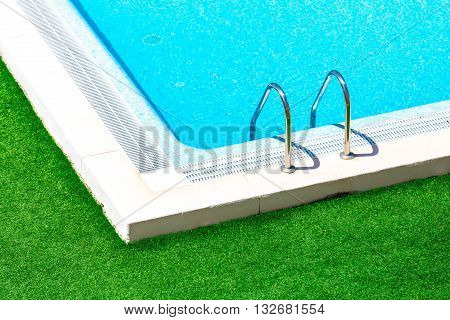 Swimming pool with stair at hotel close up.Beautiful swimming pool with green grass around.Swimming pool with blue clear water.