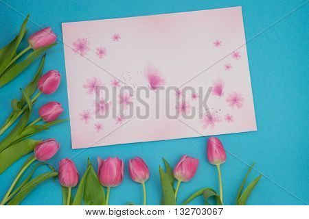 Pink tulips makig flower border on blue background with a space for your text