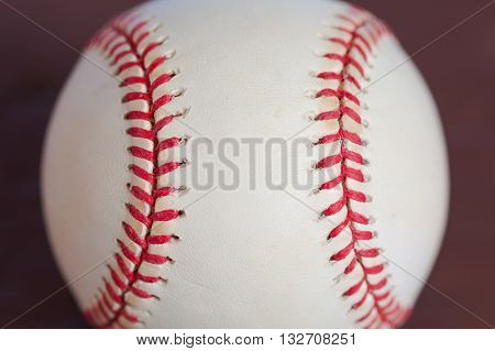 Baseball up close showing red stitches going up and down