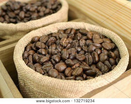 Coffee beans in brown bag sack on wooden table. (selective focus)