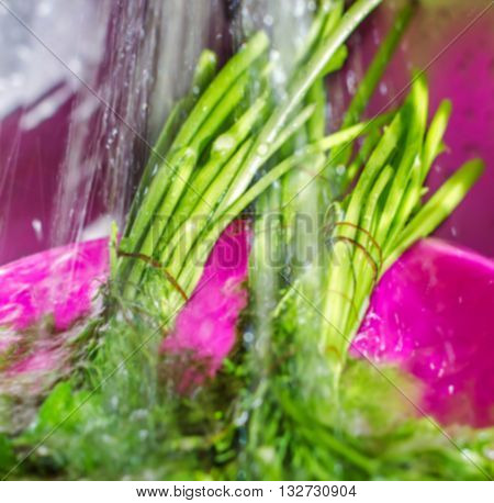 blur the background for a background wash fresh dill and parsley under water in the kitchen for cooking healthy meals blurred