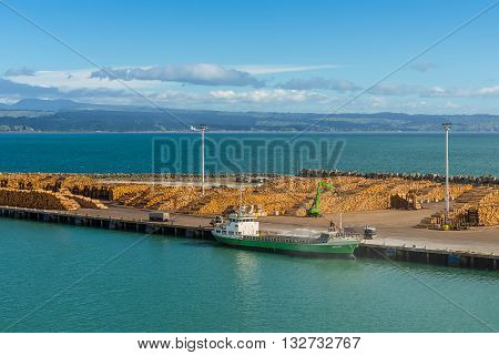 Wellington New Zealand - November 18 2014: NZ export logs all stack up wait for the next ship to come in at Port of Wellington New Zealand. Cargo ship Anatoki foreground and timber ready for export.