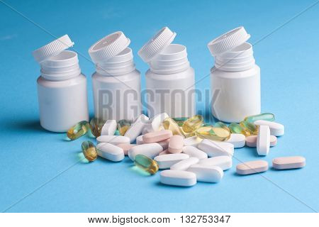 Many pills and tablets isolated on light blue background. Pharmaceutical medicament cure in container for health. Antibiotic painkiller closeup. Copy space for text.