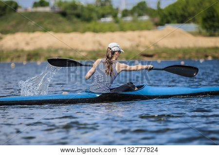 girl at rowing kayak on lake during competition. spray of water under oars