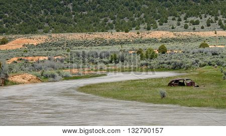 a rusty car frame sits beside the Sevier River in Utah