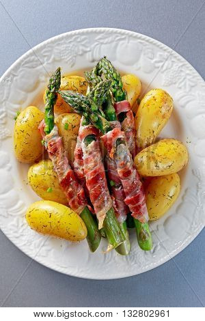 Bacon Wrapped Asparagus with young potato on plate.