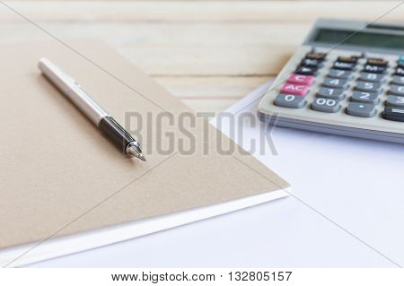 Blank white notebook with pen on wood desk. shallow depth of field