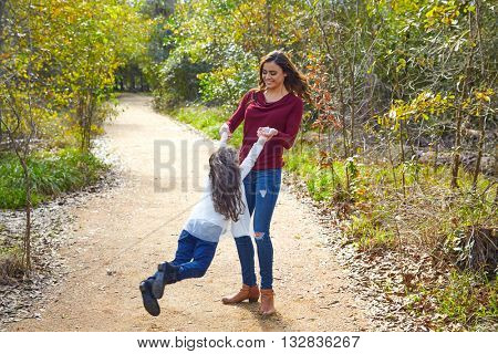 Mother and daughter being spun in circles at park having fun