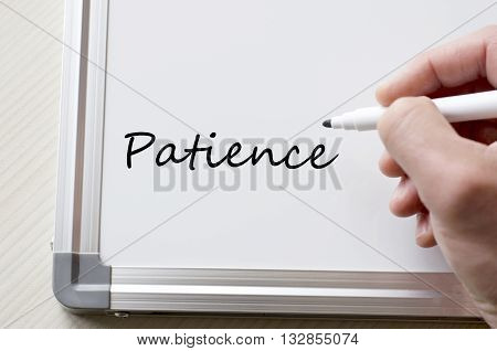 Human hand writing patience on whiteboard .