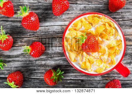 corn flakes with milk and strawberry in a red cup on an old rustic table studio lightrs close-up top view