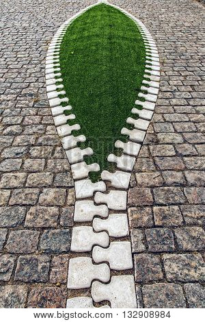 Artistic sidewalk zip reveals green grass for an environmental concept.