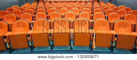 in an small theater there are orange seats in a row