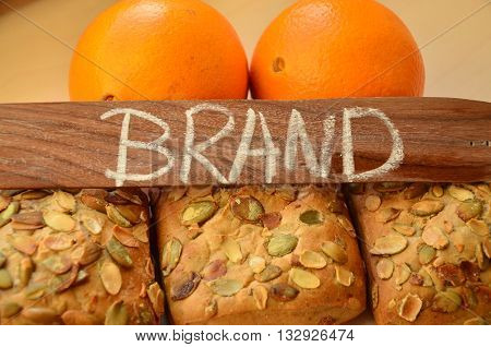 the word brand on the background of fresh bread rolls and fresh orange