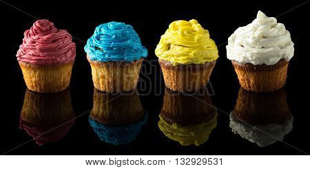 four colorful muffins on black with reflection