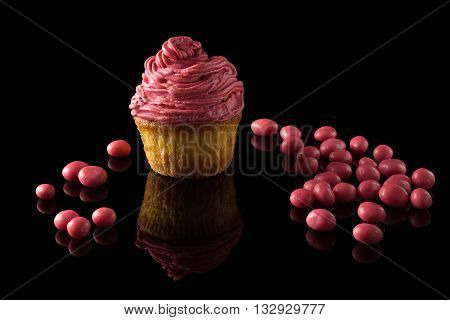 one pink muffin on black with reflection
