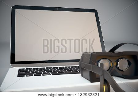 Front view of virtual reality glasses next to computer with blank screen. Mock up 3D Rendering