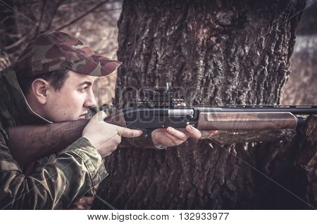 Hunter man with gun aiming and prepared to make a shot during hunting