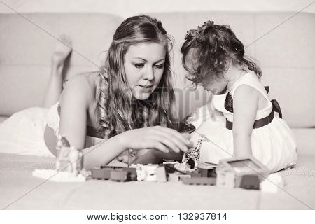 Mother with a little daughter playing with blocks at home