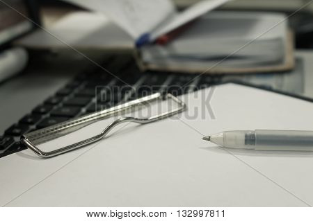 Gel pen lies on a plate with white paper, notebook with a block on the background