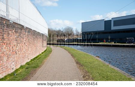 The Paved Towpath And Small Metal Bridge Over The Canal