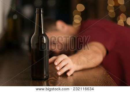 Man reaching for bottle of drink in bar. Alcoholism problem