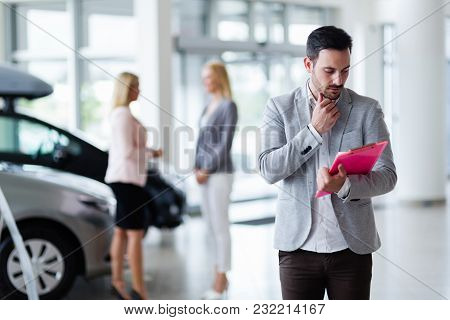 Handsome Young Salesman At Car Dealership Selling Vehichles