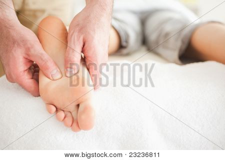 Massagista masculino pé de uma mulher em uma sala de massagem