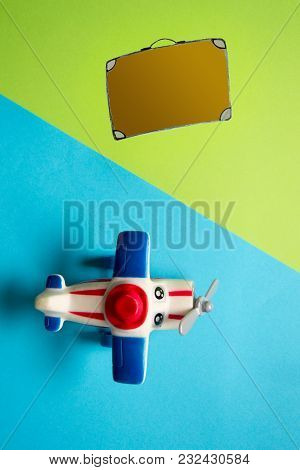 Flat Lay Design Of Travel Concept With Plane And Travel Bag On Blue And Pink Background.