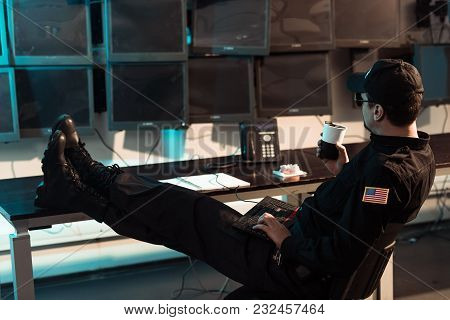 Prison Guard Sitting With Legs On Table And Monitoring People In Jail