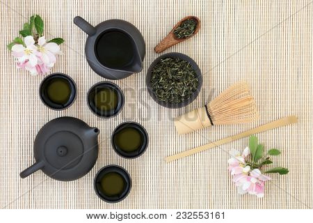 Japanese sencha sukiygu makoto tea with teapot, leaves, cups, whisk, stick stirrer and spring blossom on bamboo background. Has many health benefits including boosting  the immune system.