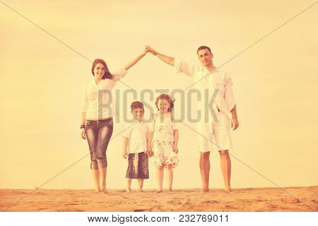 happy young family have fun on beachand showing home sign with conncected hands while protecting childrens