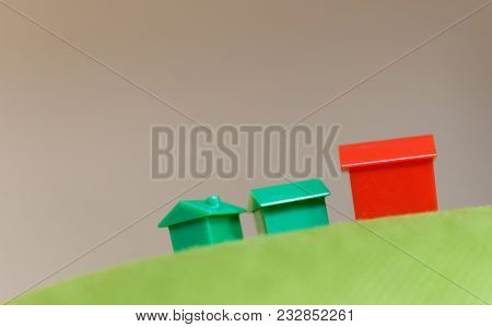 Miniature Monopoly Houses On Top Of A Green Height