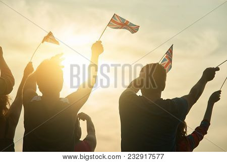 Young People Waving British Flags, Back View. Bright Gloving Sunshine.